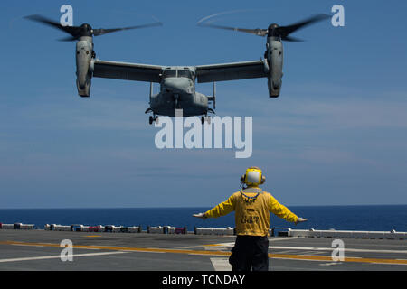 A Sailor guides an MV-22 Osprey tiltrotor aircraft during flight operations aboard the USS Wasp (LHD 1) while underway in the Philippine Sea, June 5, 2019. The 31st MEU, the Marine Corps` only continuously forward-deployed MEU, provides a flexible and lethal force ready to perform a wide range of military operations as the premier crisis response force in the Indo-Pacific region. (Official U.S. Marine Corps photo by Lance Cpl. Kenny Nunez Bigay)